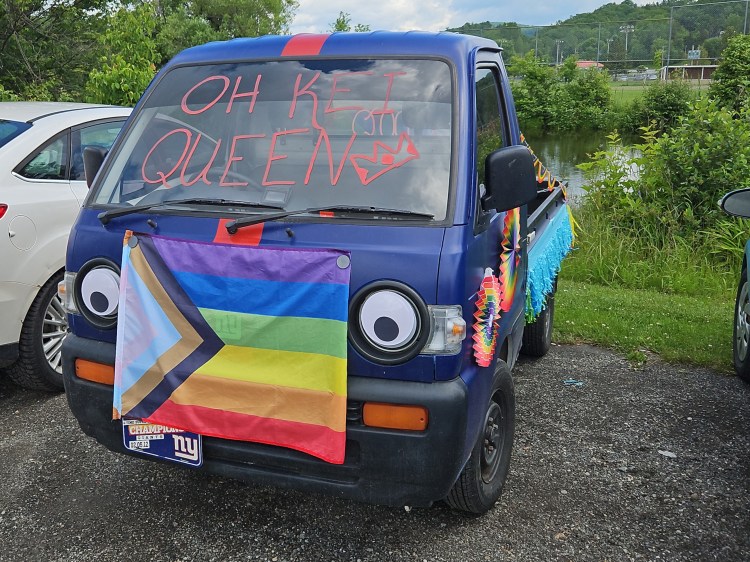 Kei car, a little cab over engine truck, with rainbow flag and "Oh Kei Queen" written on the windshield