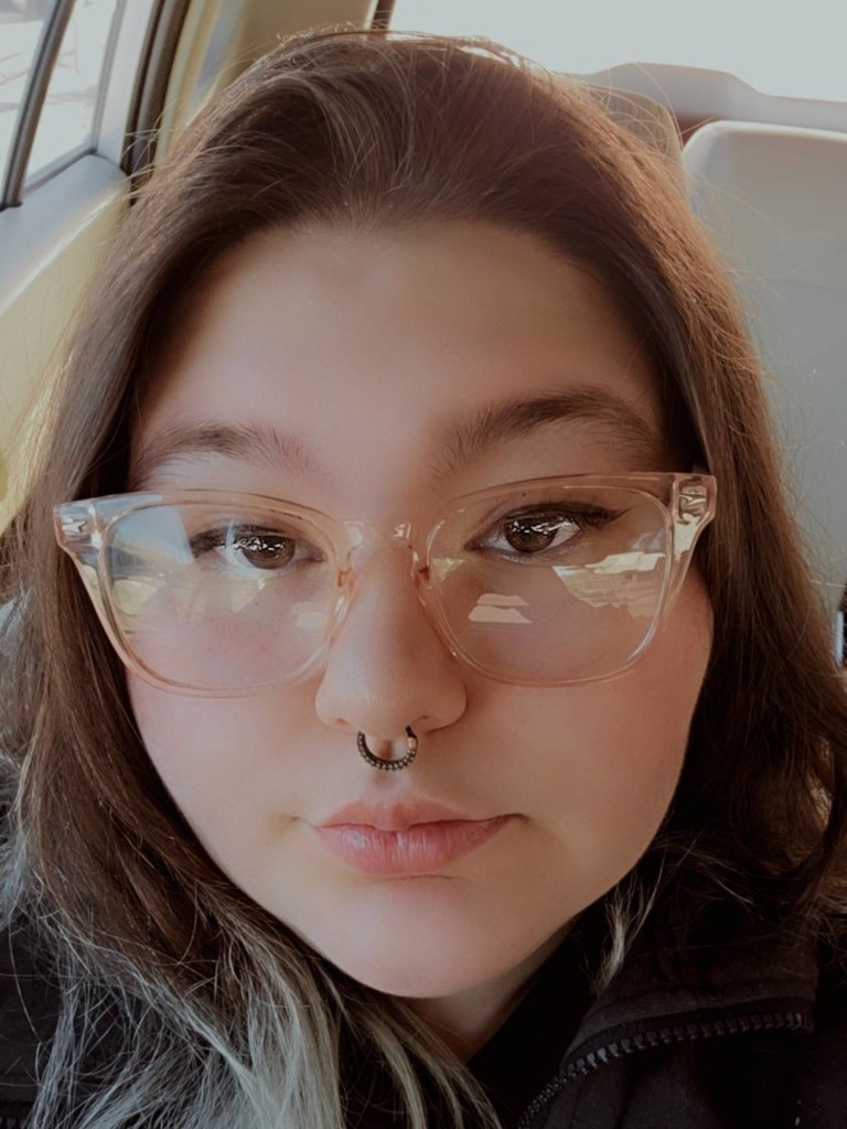 Person with long brunette hair and cats-eye glasses